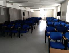 Sala szkoleniowa w budynku WSB przy al. Grunwaldzkiej w Gdańsku, widok na krzesła tapicerowane z pulpitami oraz rzutnik multimedialny